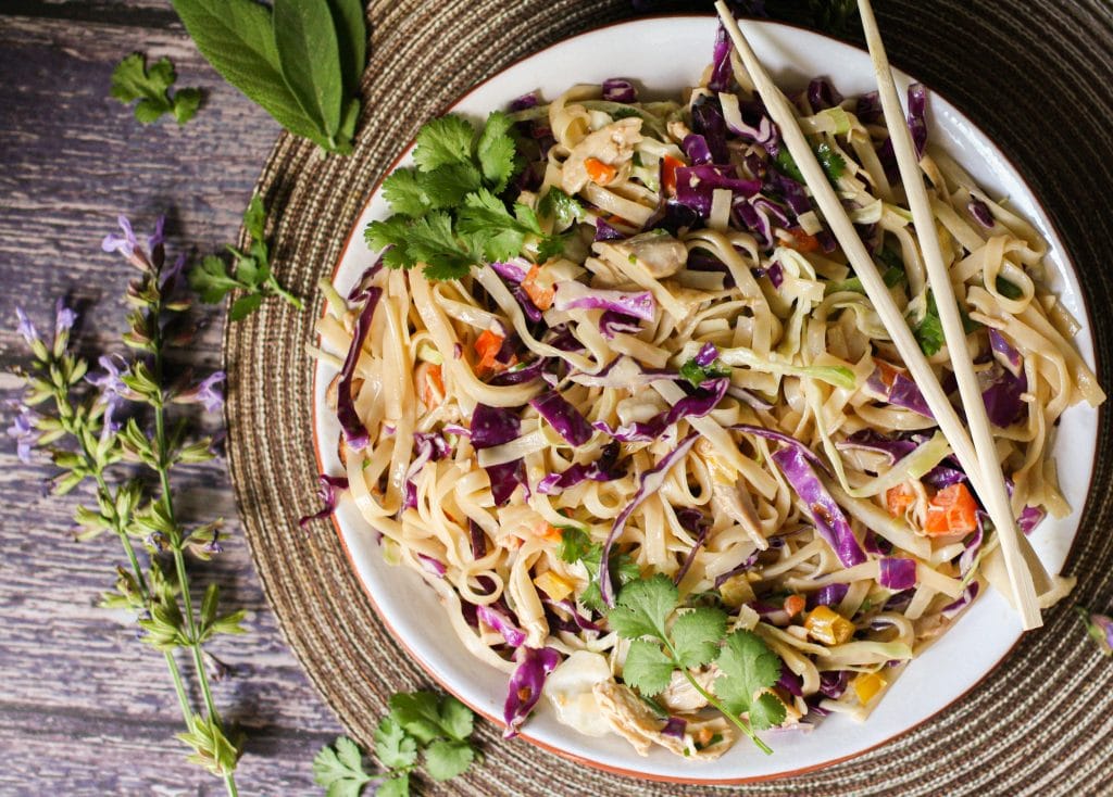 Noodles, red cabbage and bell peppers in a white bowl