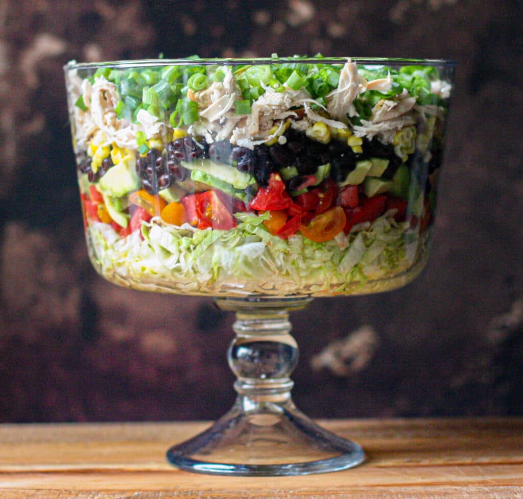 Layered Southwest Salad with Avocado Lime Ranch Dressing in a glass trifle bowl
