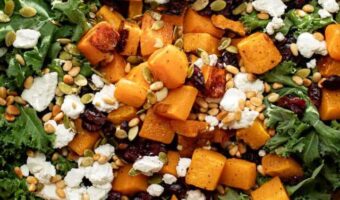 roasted butternut squash salad in a wooden bowl with goat cheese, pine nuts and cranberries