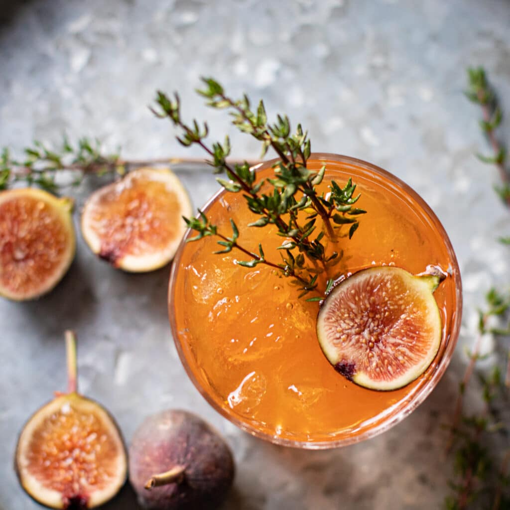 Top down view of an Old Fashioned cocktail with fresh figs and thyme