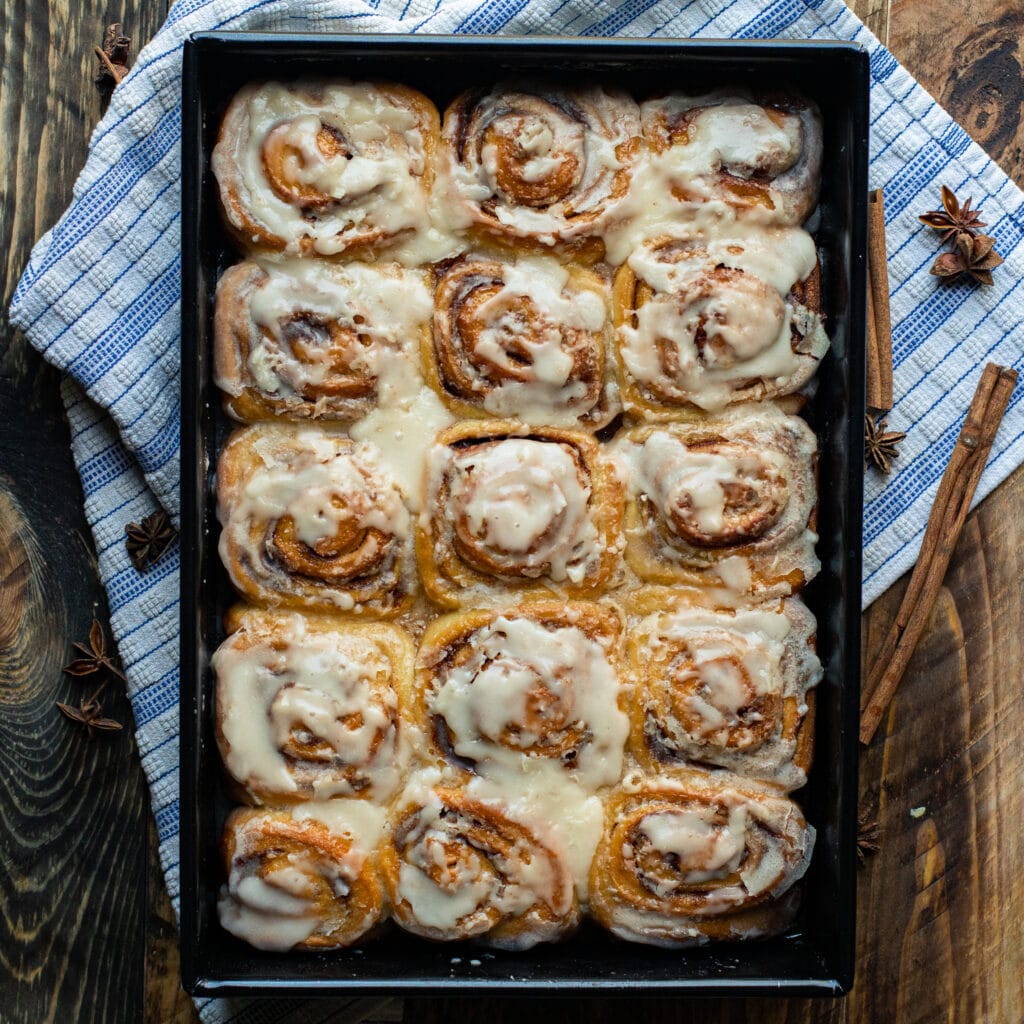 Classic Cinnamon Rolls with Vanilla Frosting in a black baking dish
