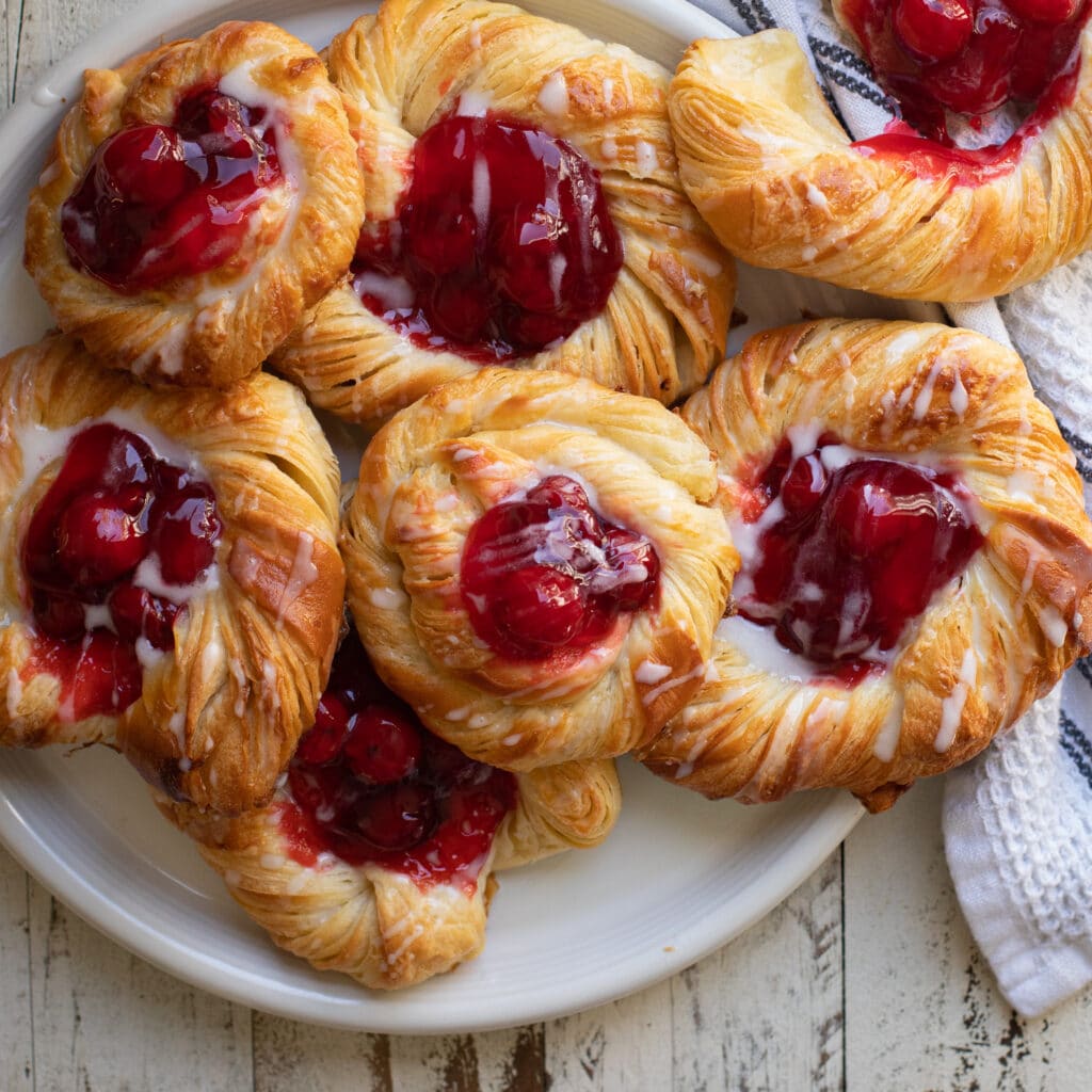 A pile of cherry danish on a white plate.