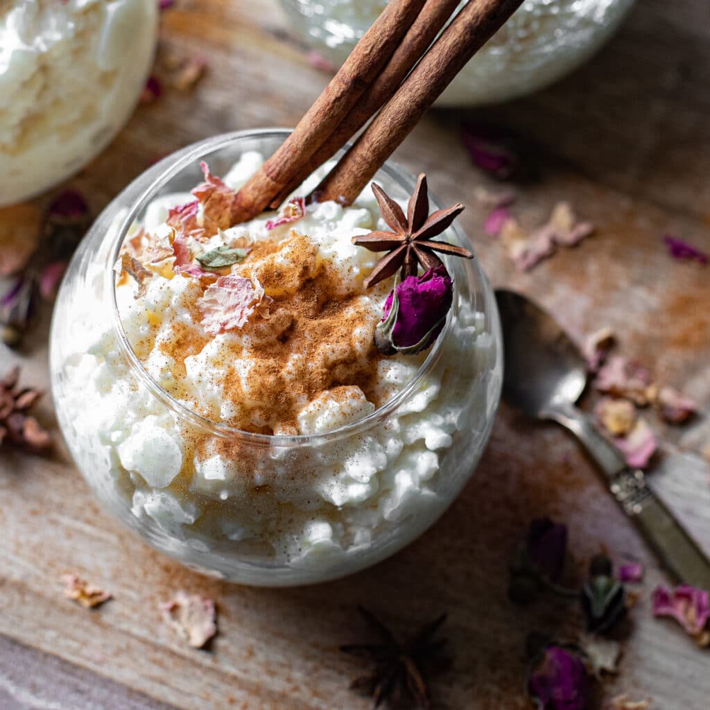 Stovetop Rice Pudding in a glass serving dish with star anise and cinnamon sticks
