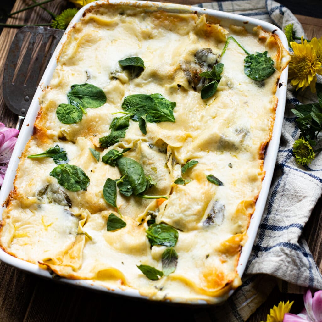 Lasagna with white sauce in a large white casserole dish.
