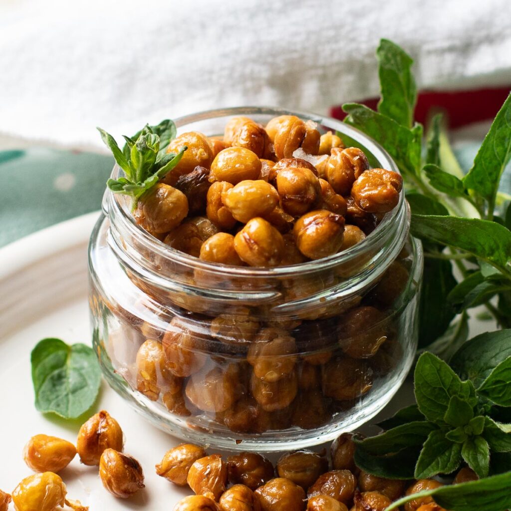 roasted chickpeas in a glass jar garnished with fresh oregano
