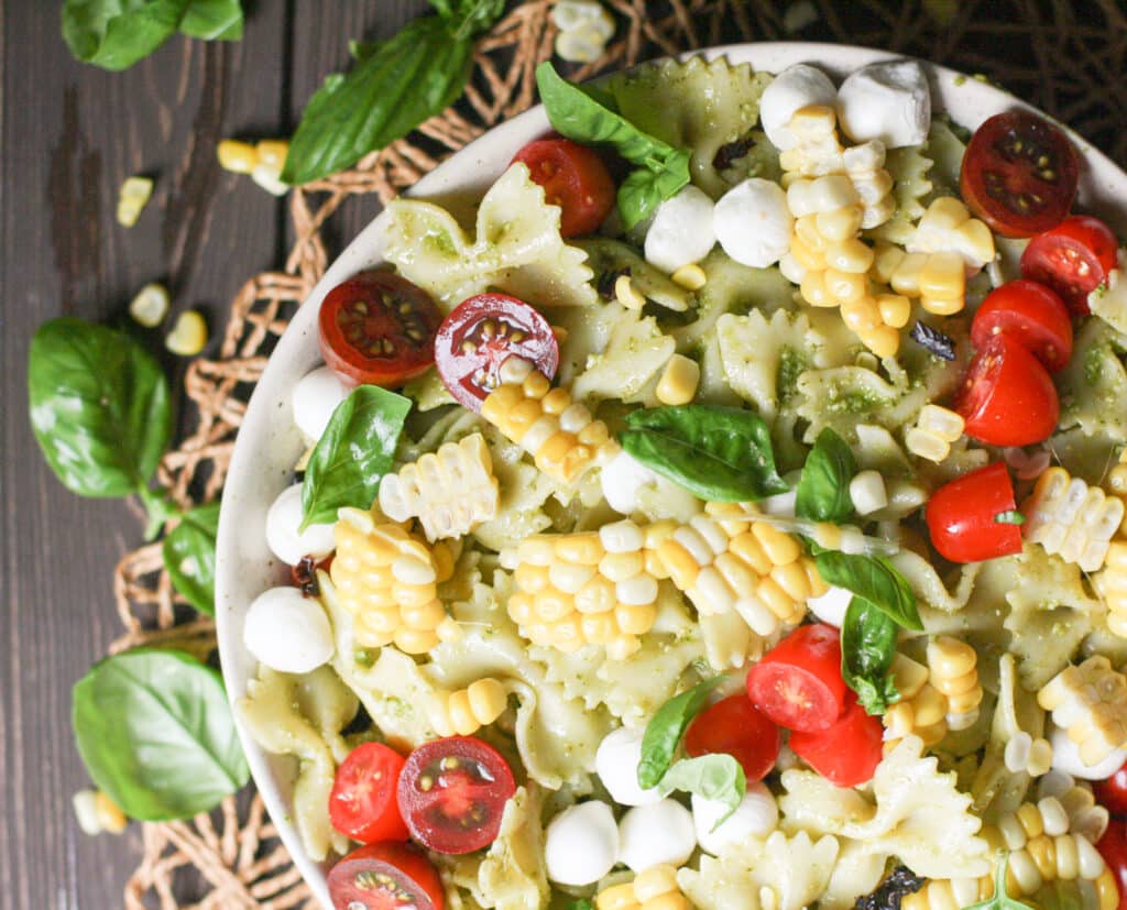 bowtie pasta salad in a bowl, garnished with fresh basil and tomatoes