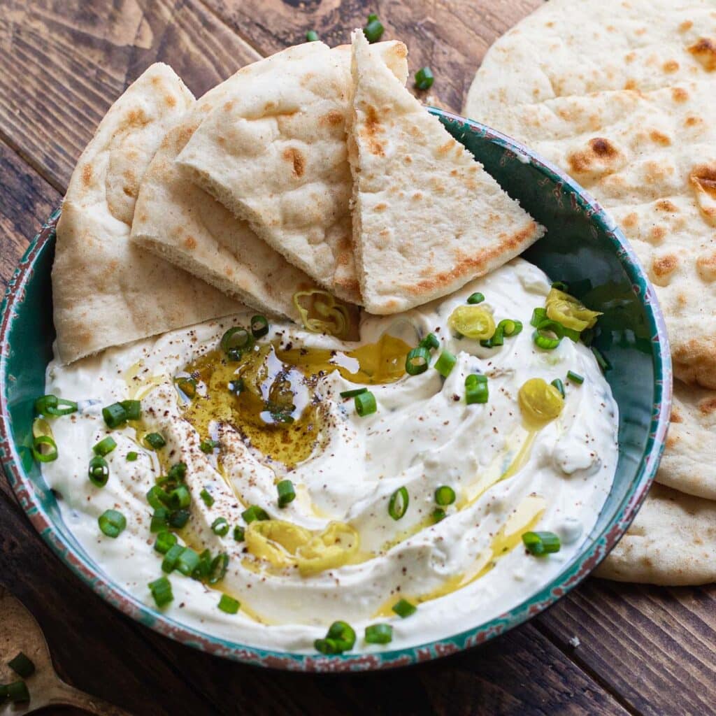 Greek feta dip in a green bowl garnished with scallions