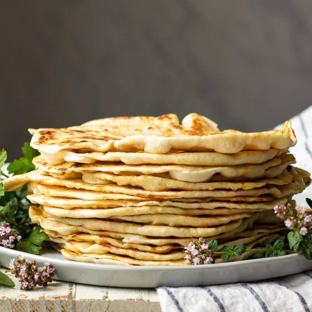 A stack of pita bread garnished with fresh oregano flowers