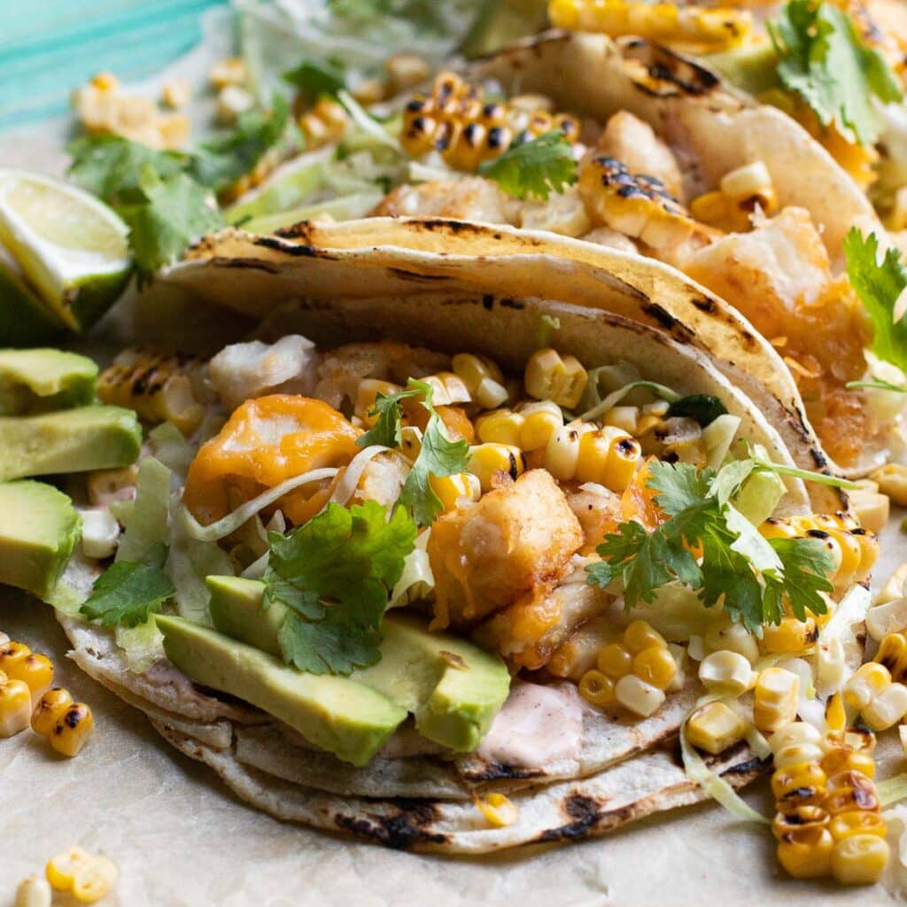 close up view of one fish taco with avocado, corn and cilantro