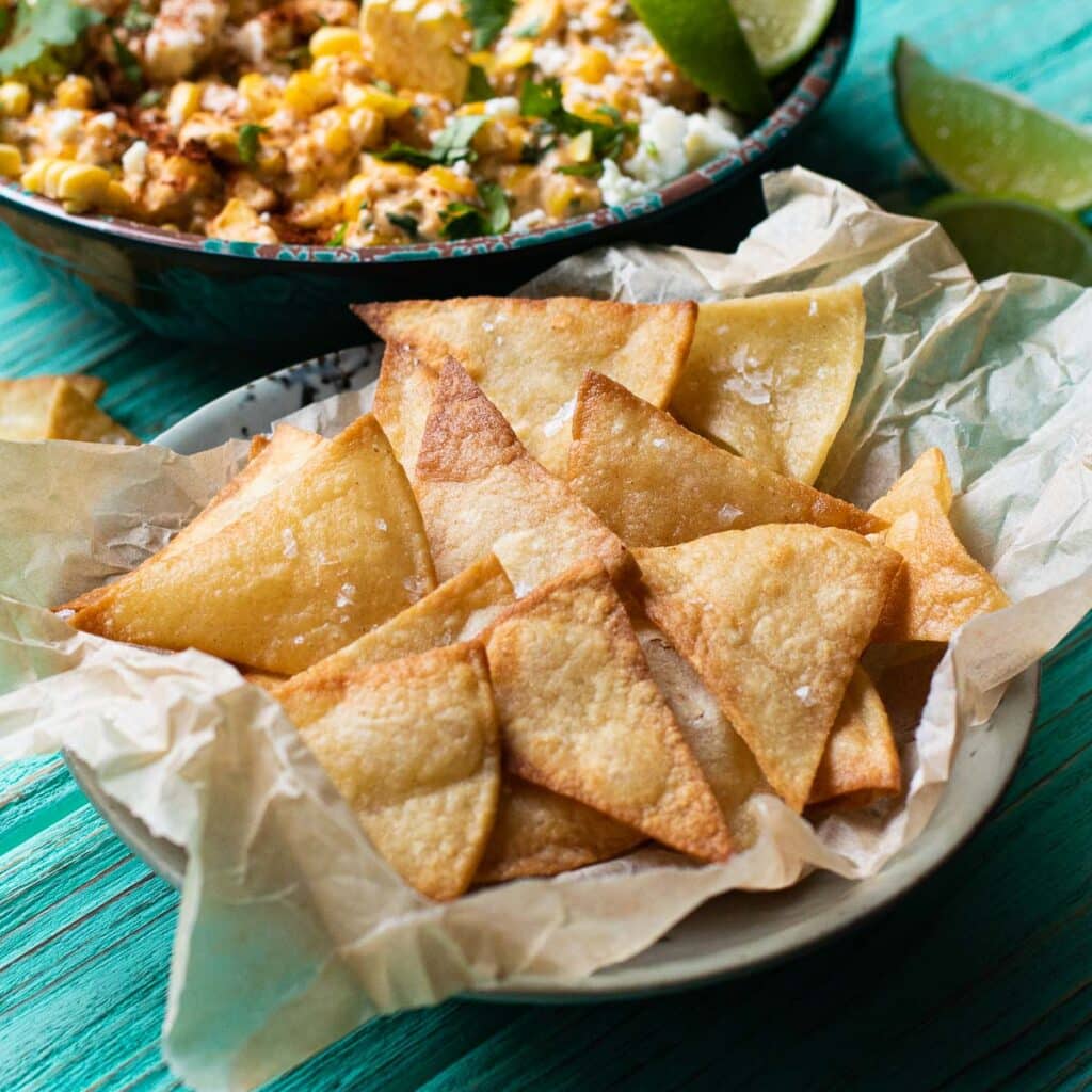 Homemade tortilla chips in a basket lined with parchment paper