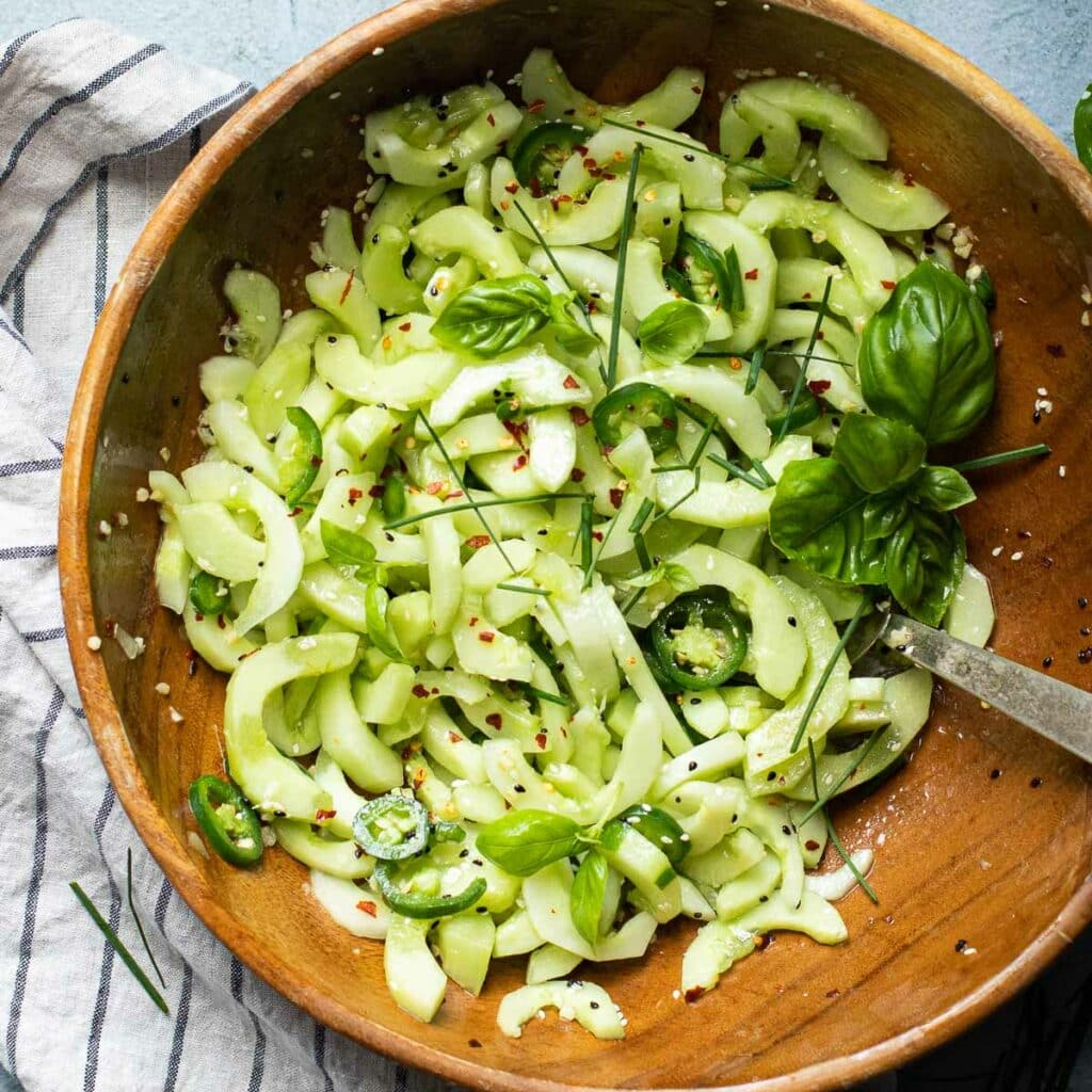 Asian Cucumber Salad with  jalapeño peppers, fresh basil in a wooden bowl
