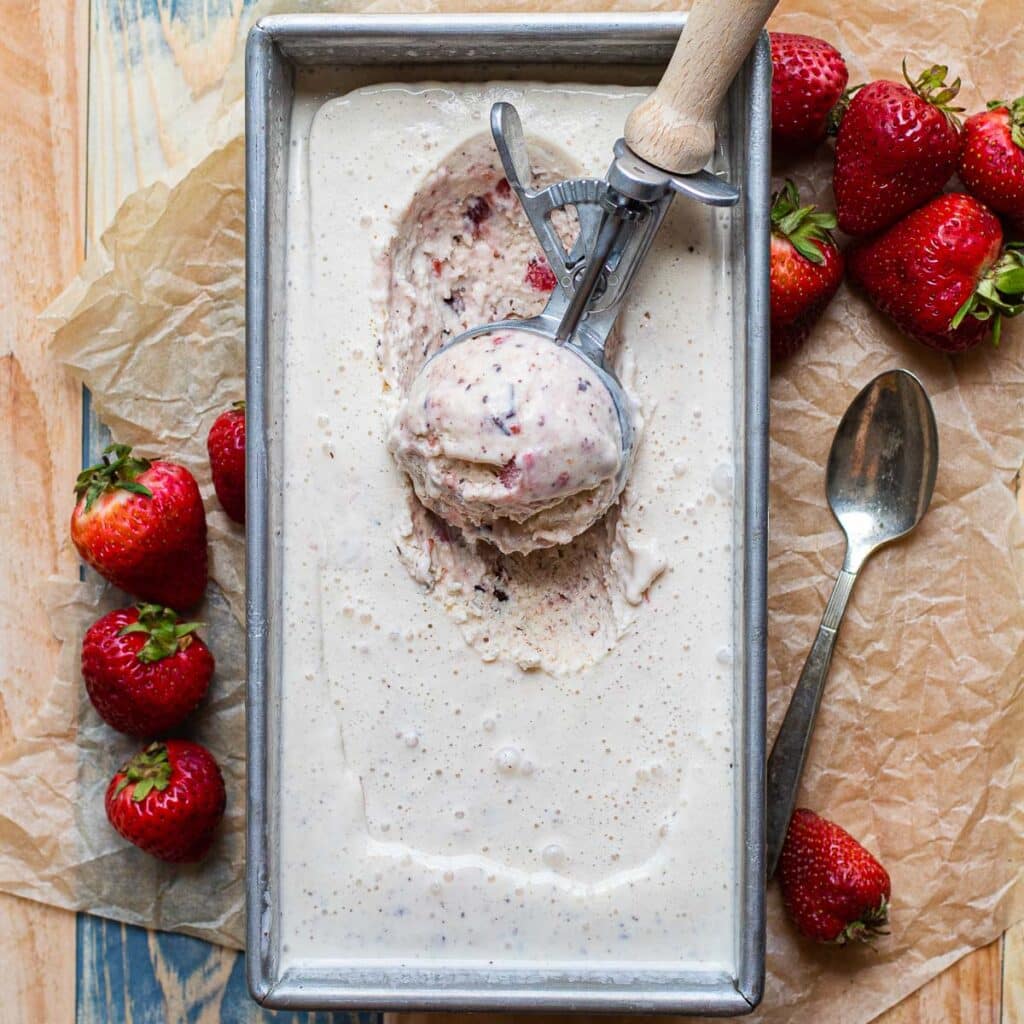 Strawberry Chocolate Chip Ice Cream in a metal container with an ice cream scooper