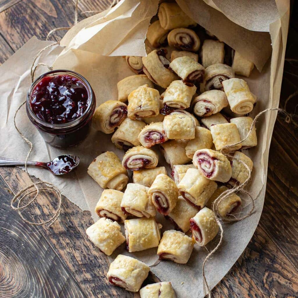 Jewish Raspberry Rugelach cookies coming out of a bakery box lined with brown parchment paper