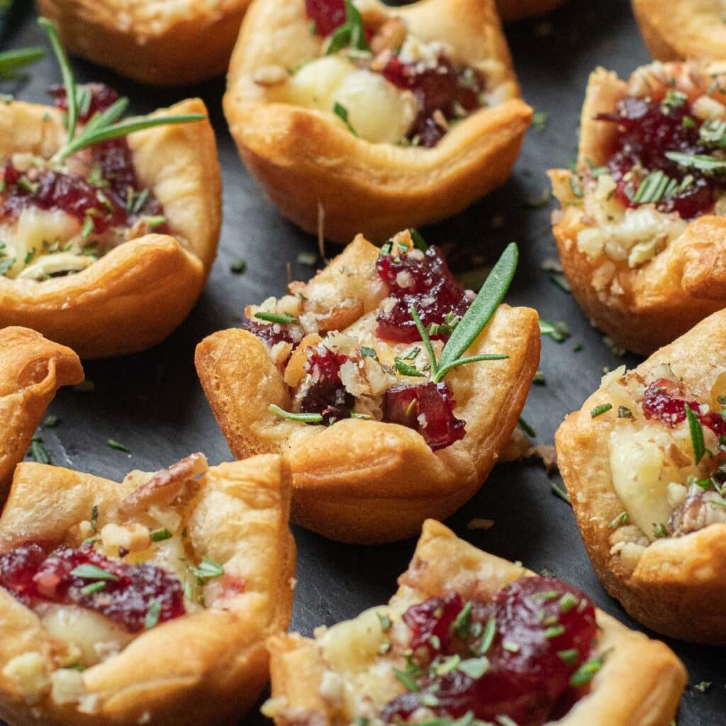 cranberry and brie bites with fresh rosemary and chopped pecans