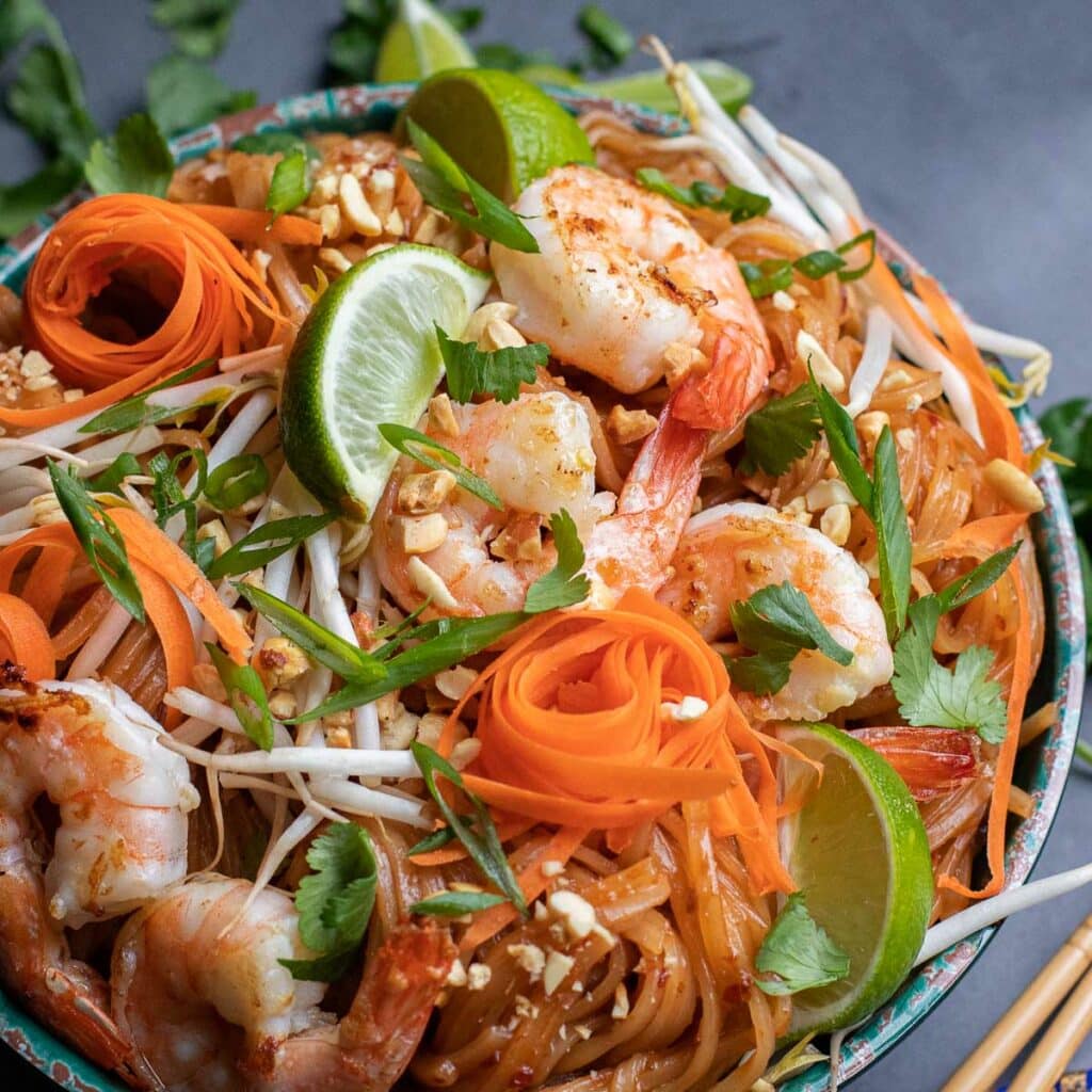 gluten free pad thai noodles with shrimp, lime wedges, shredded carrots and scallions