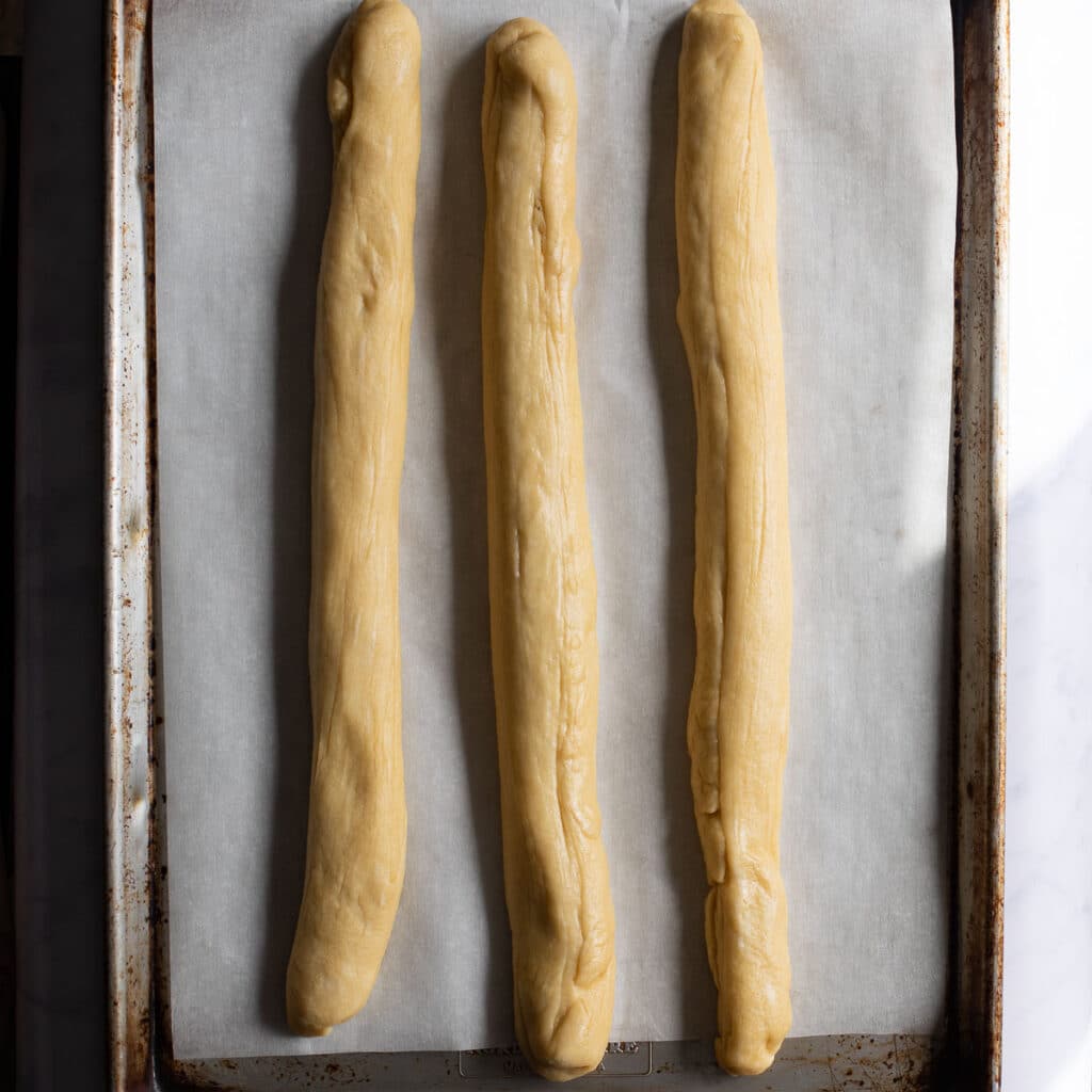three long ropes of challah dough, lined up parallel to each other