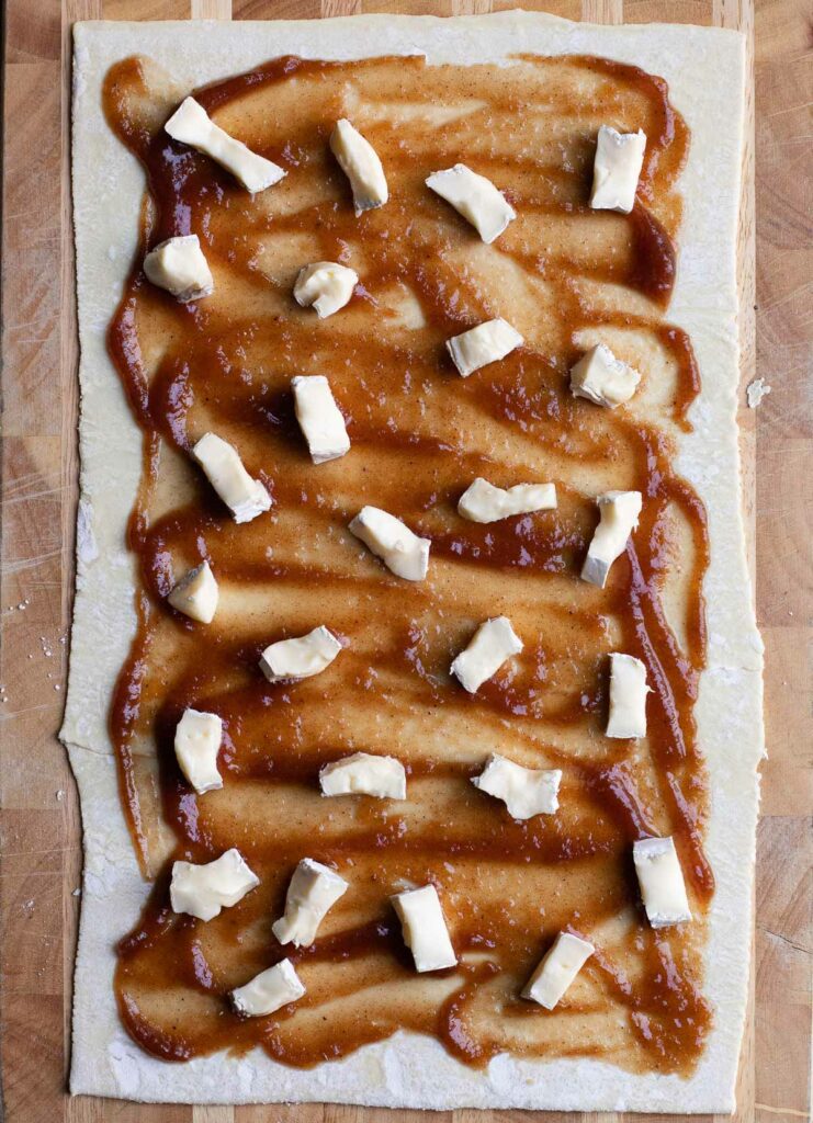 a sheet of puff pastry, smeared with apple butter and dotted with cubes of brie cheese