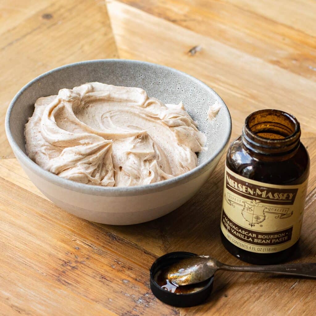 cinnamon vanilla frosting in a bowl next to an open jar of vanilla bean paste