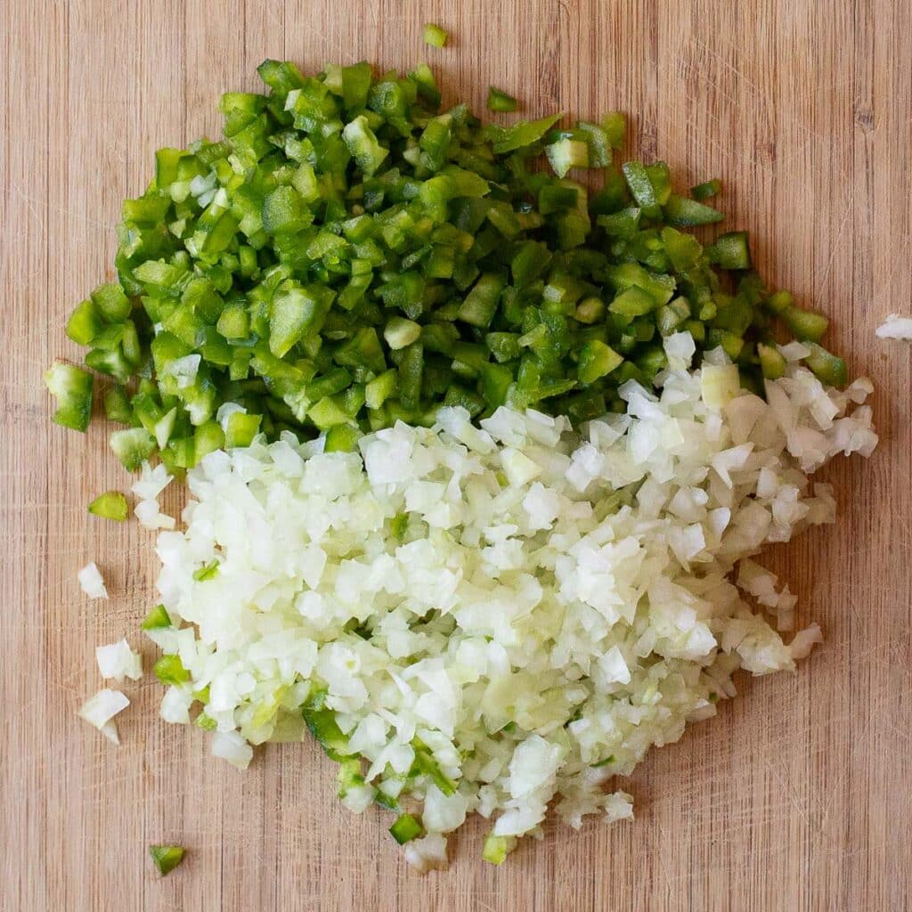 diced onions and diced green bell peppers on a wooden board