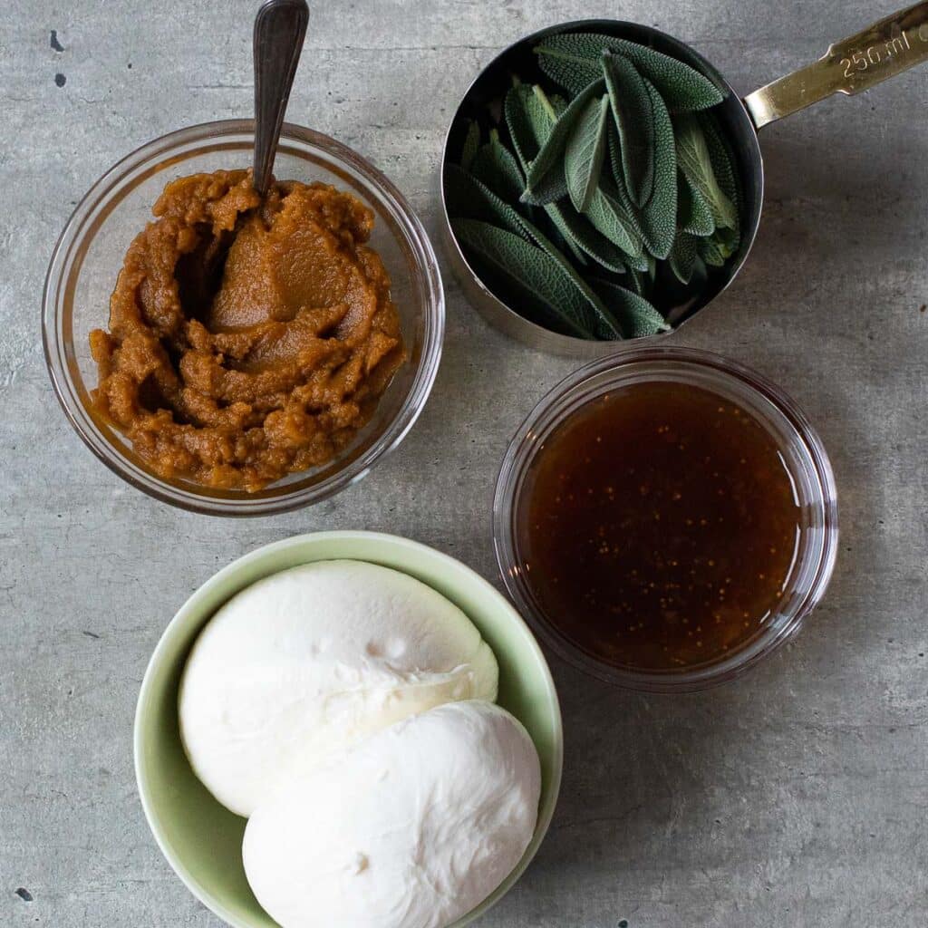 Ingredients to make burrata toast: burrata cheese, fig syrup, sage leaves and pumpkin butter