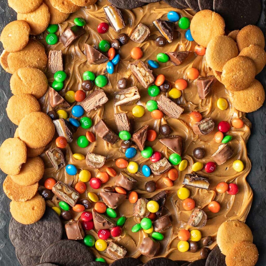 Peanut Butter Board with chocolate candy and cookies on a black slate board