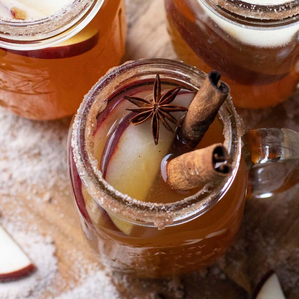 mulled spiked cider in a mason jar, garnished with cinnamon sticks and star anise
