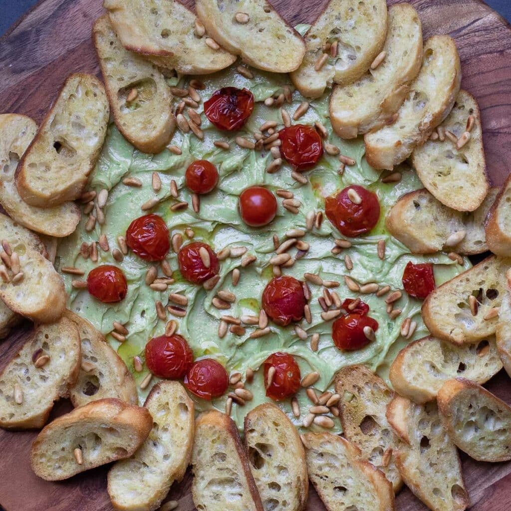 butter board with pesto, cherry tomatoes and toasted baguettes