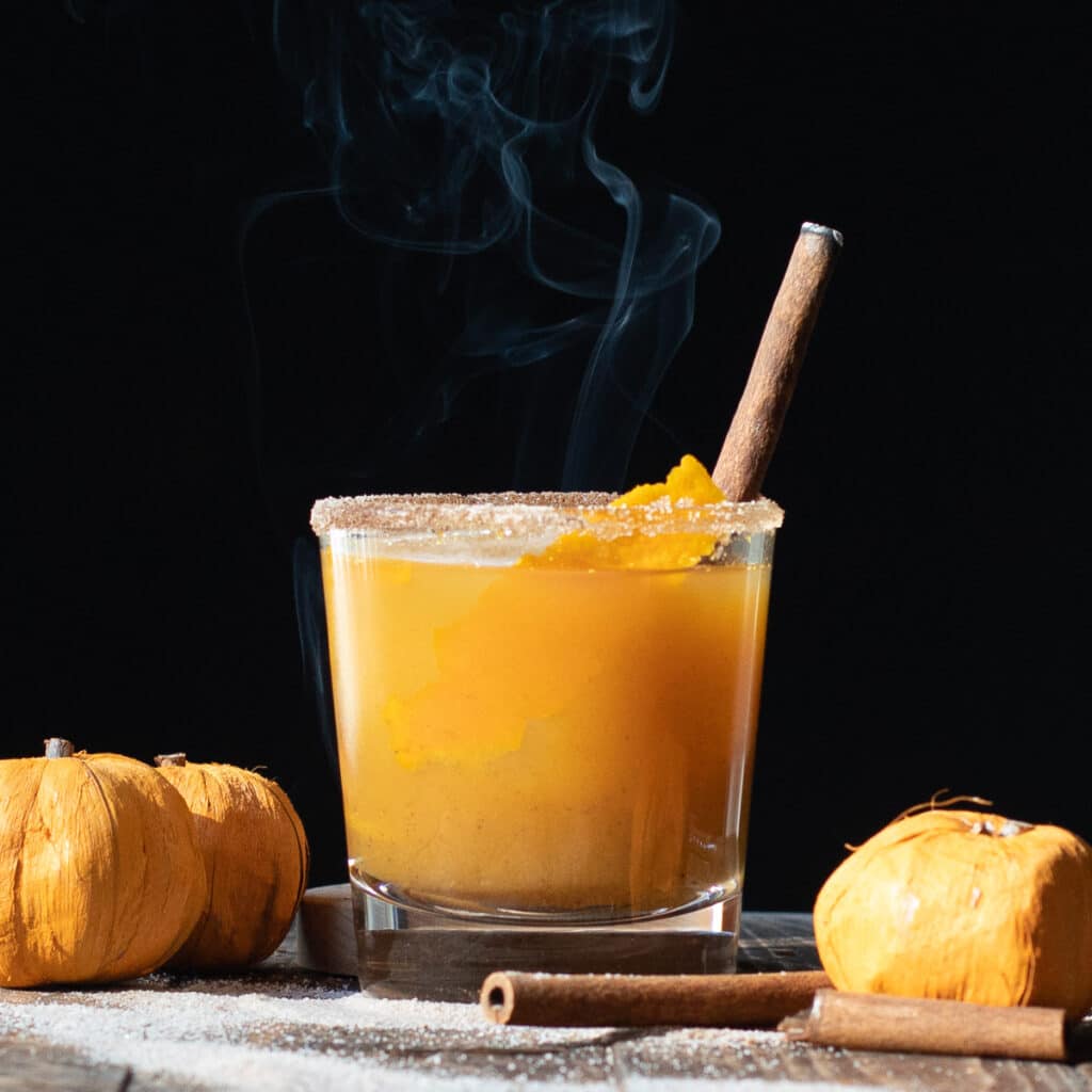 Pumpkin Pie Bourbon Cocktail in a rocks glass with a smoking cinnamon stick