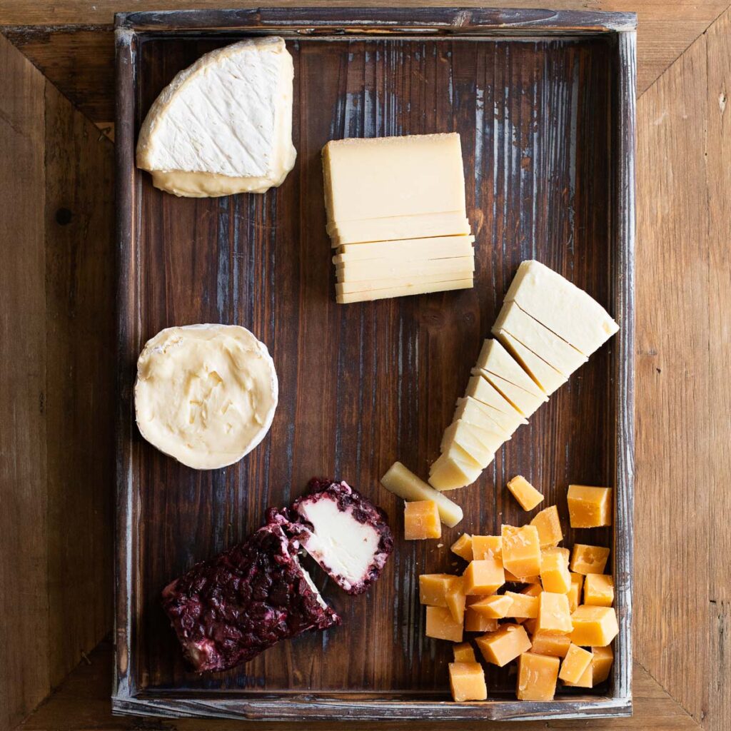 Cheeses arranged on a wooden serving board