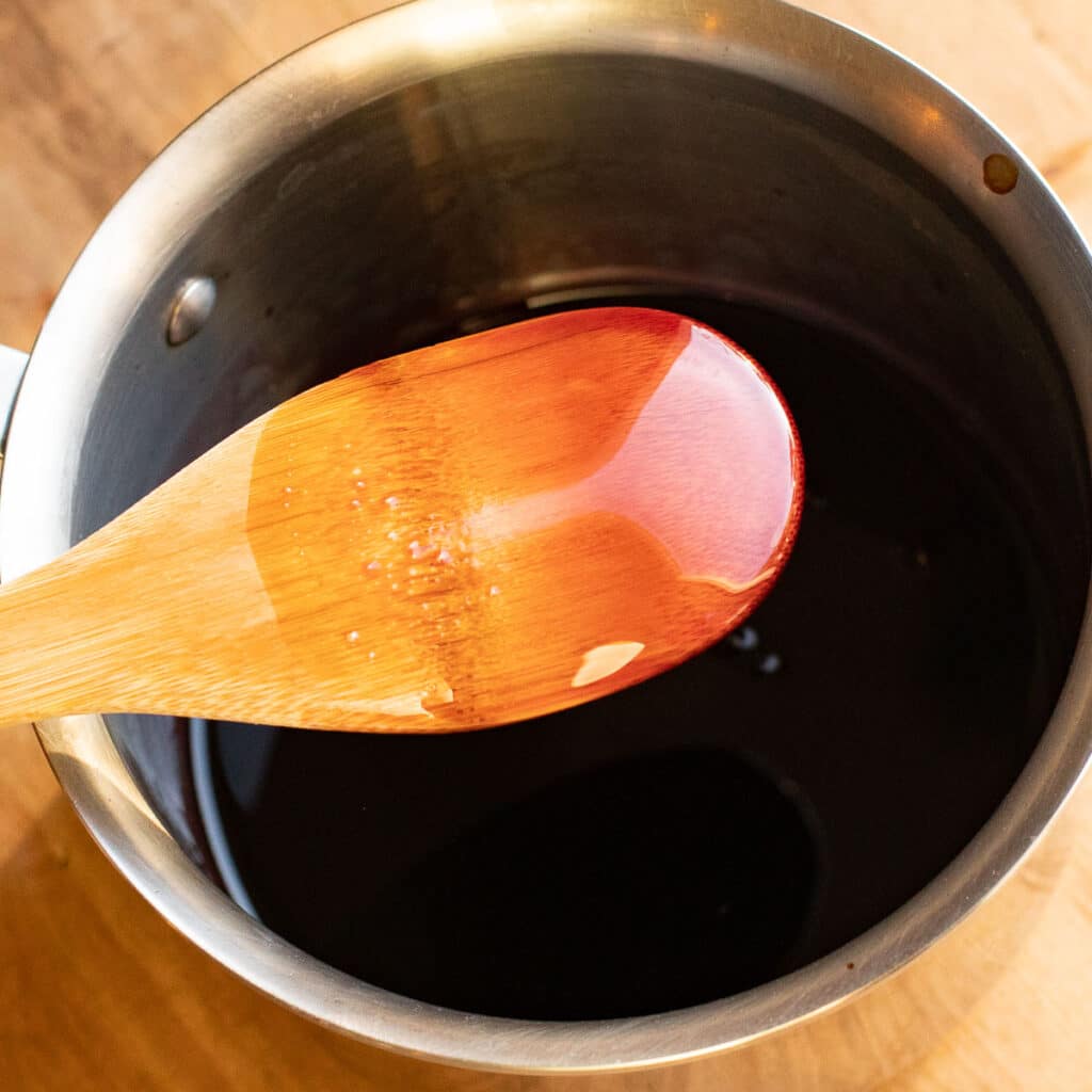 Pomegranate syrup coating the back of a wooden spoon