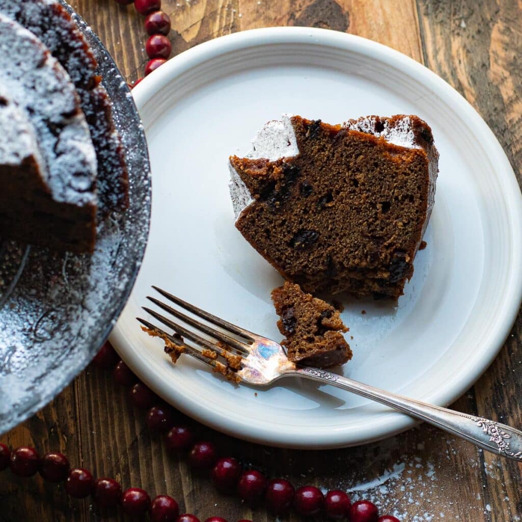 A slice of Holiday Spice Cake on a white plate with a silver fork