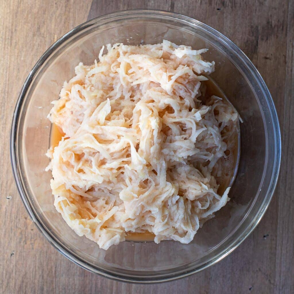 Shredded potatoes in a glass bowl