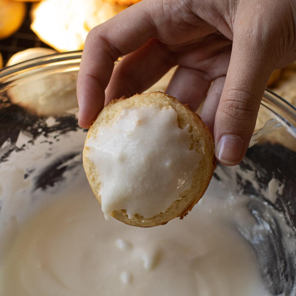 A cookie being dipped into lemon frosting
