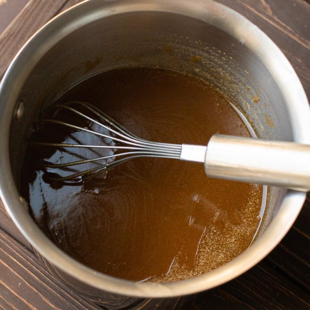 Melted brown sugar and butter in a stainless steel saucepan with a wire whisk in it