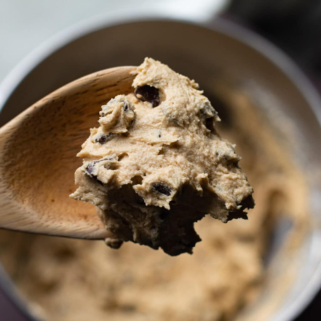 Chocolate chip cookie batter on a wooden spoon