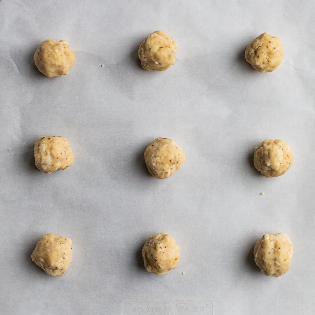 Smash cookie dough rolled into balls on a baking sheet