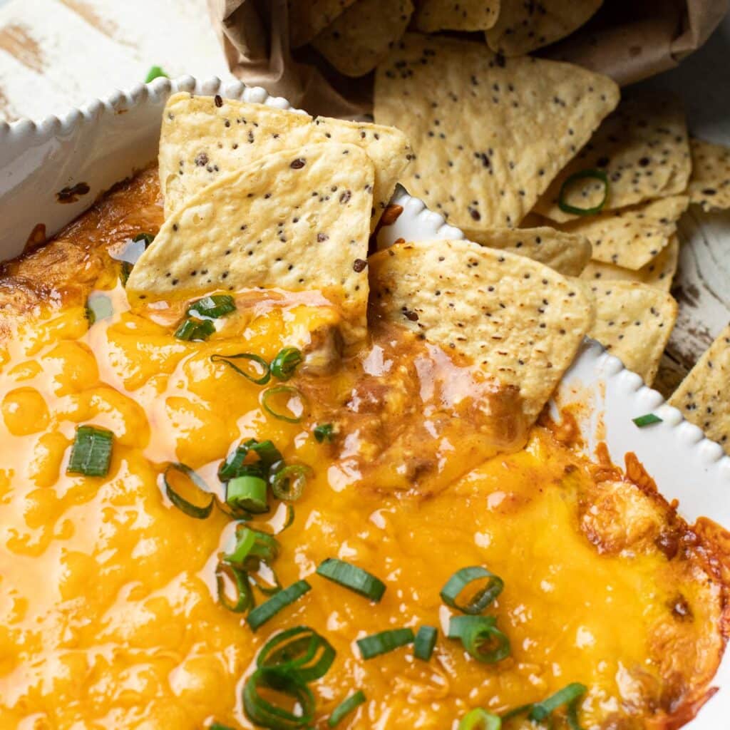 Tortilla chips dipped into chili cheese dip