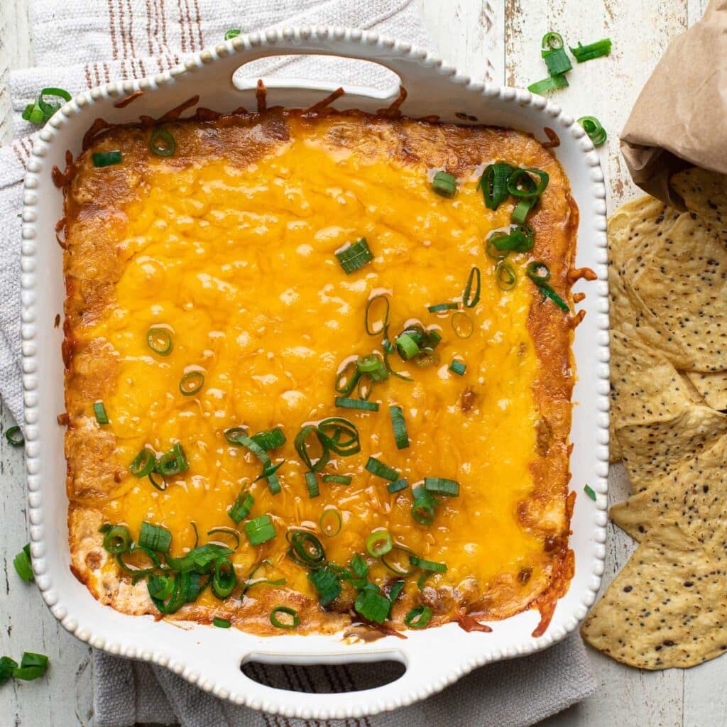 3 Ingredient Chili Cheese Dip in a white square baking dish, garnished with chopped scallions