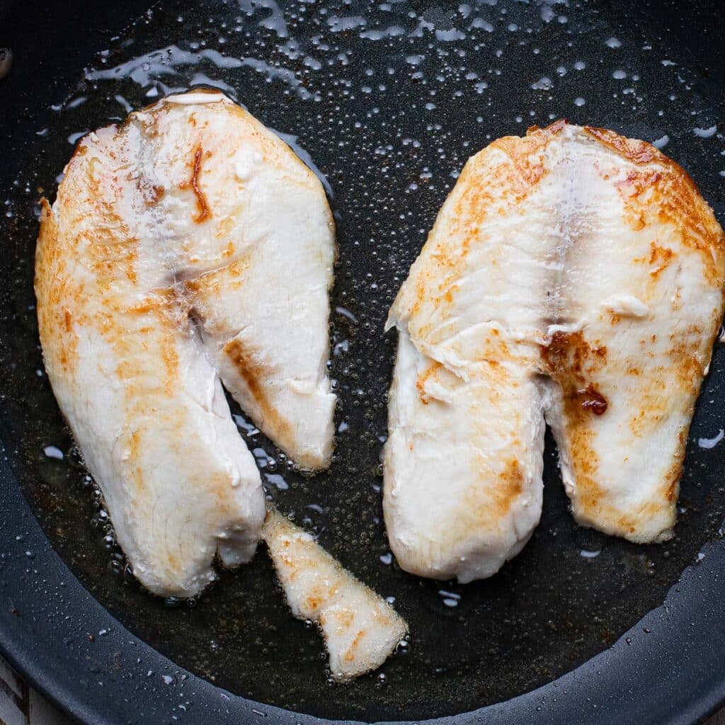 White fish fillets frying in vegetable oil in a pan