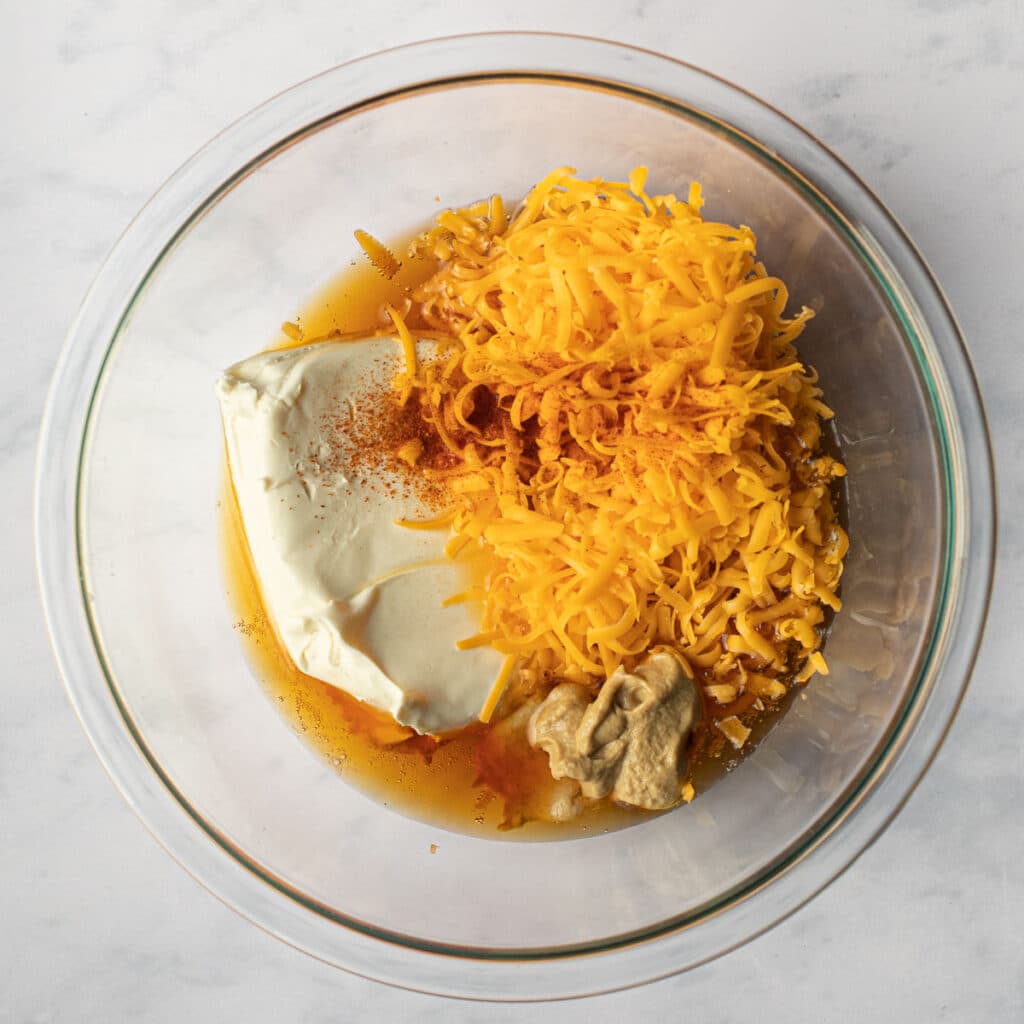 Cheddar cheese, cream cheese, Dijon mustard, lager beer and cayenne pepper in a glass bowl