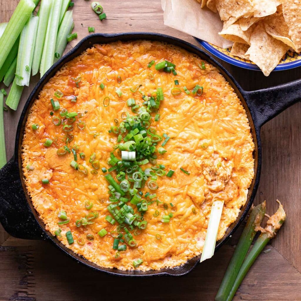 Buffalo Chicken Dip in a cast iron skillet, garnished with chopped scallions