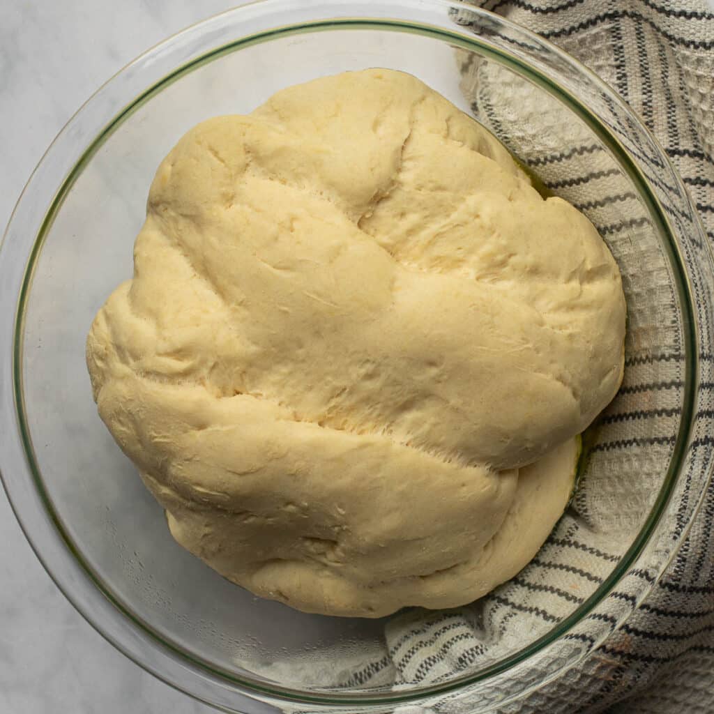 A ball of dough in a glass bowl after it has risen