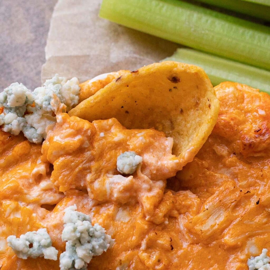 A thick corn chip dipped into low carb buffalo chicken dip