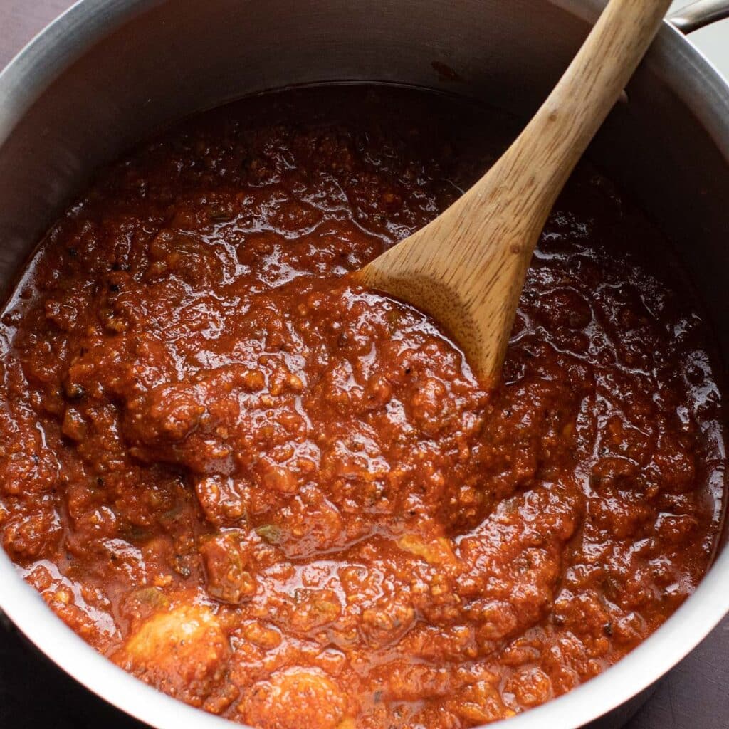 A pot of tomato sauce with a wooden spoon in it