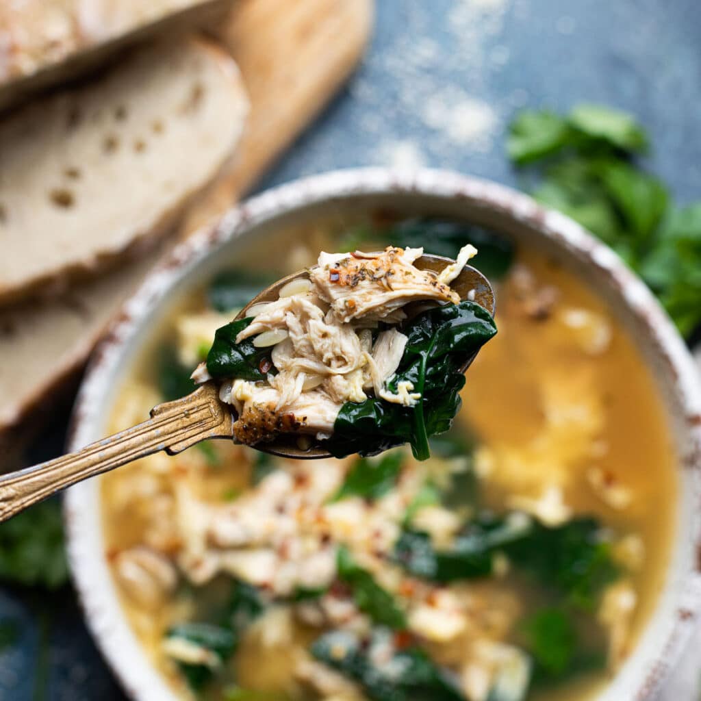 Close up of a spoon holding chicken and spinach
