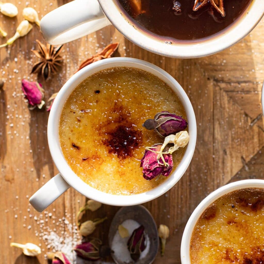 A cup of chai creme brulee decorated with dried rose buds