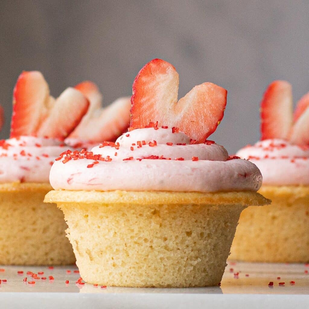 Champagne Cupcake with strawberry frosting, topped with a sliced strawberry