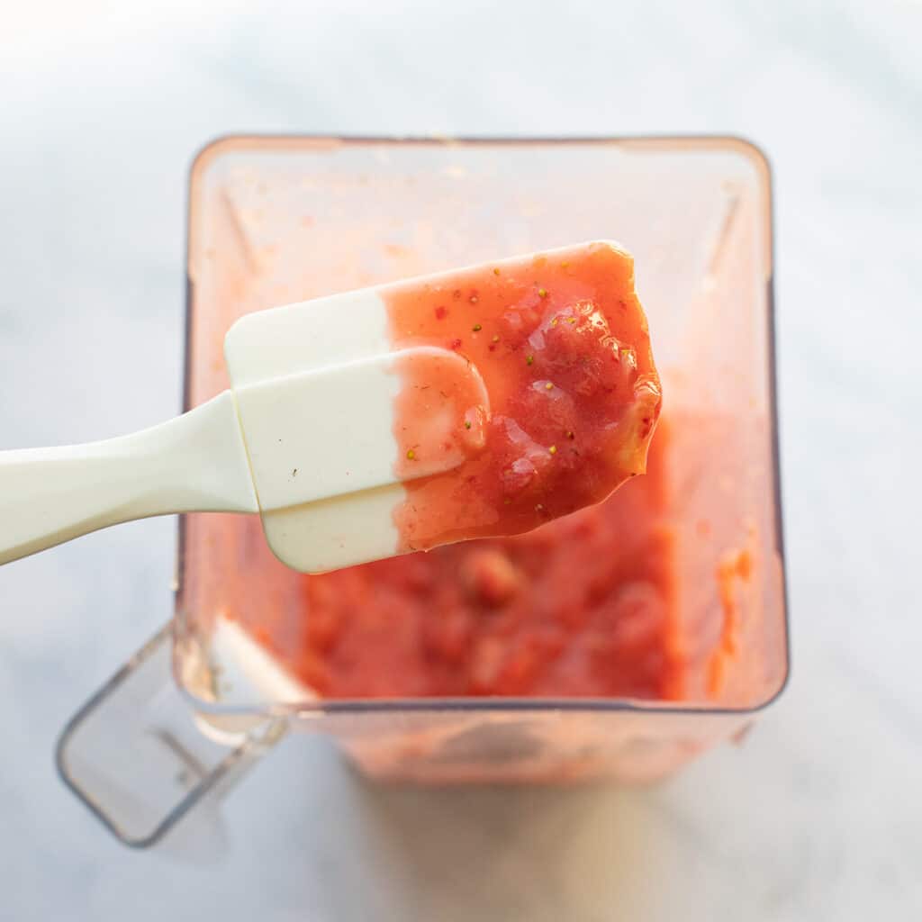 Strawberry puree in a blender with a white spatula