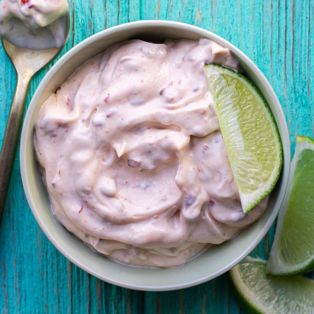 chipotle mayonnaise in a white bowl with fresh lime wedges