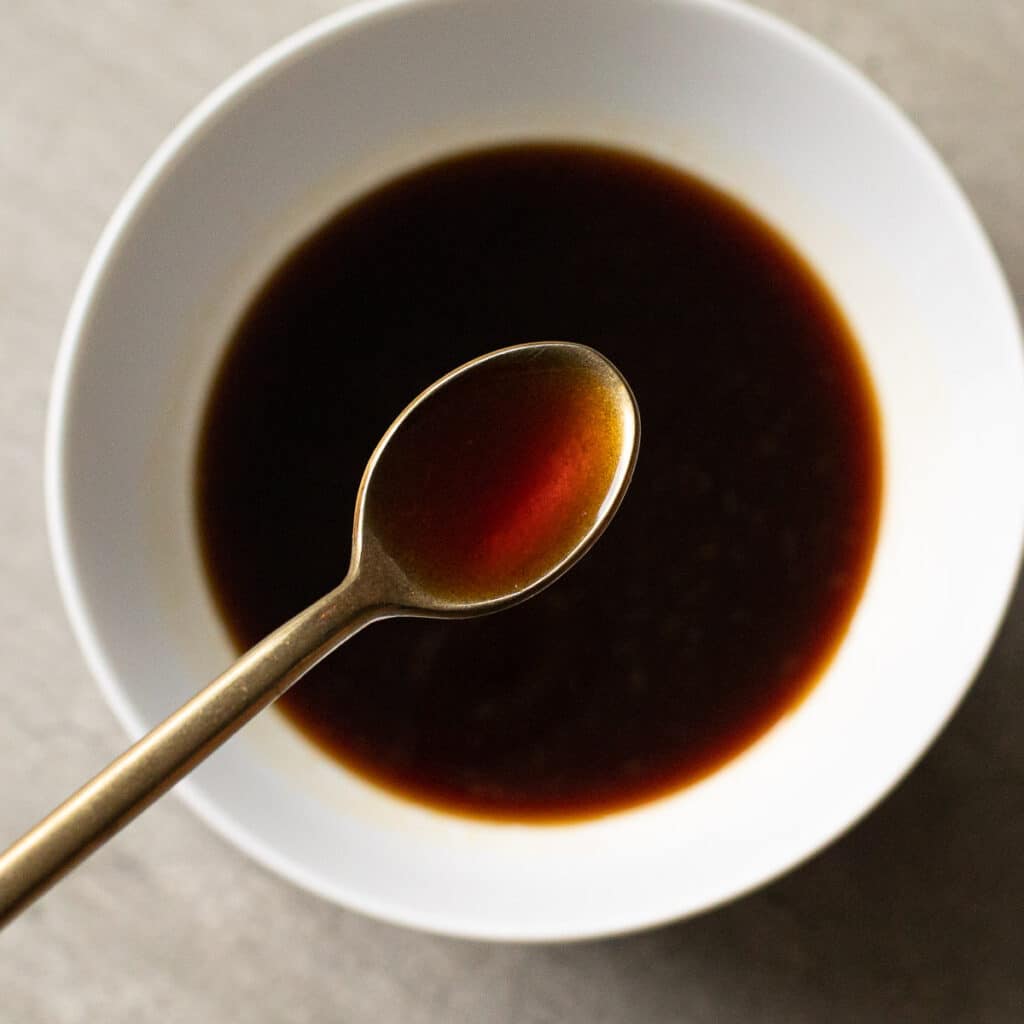 Citrus Ponzu Sauce in a white bowl with a gold spoon hovering over it
